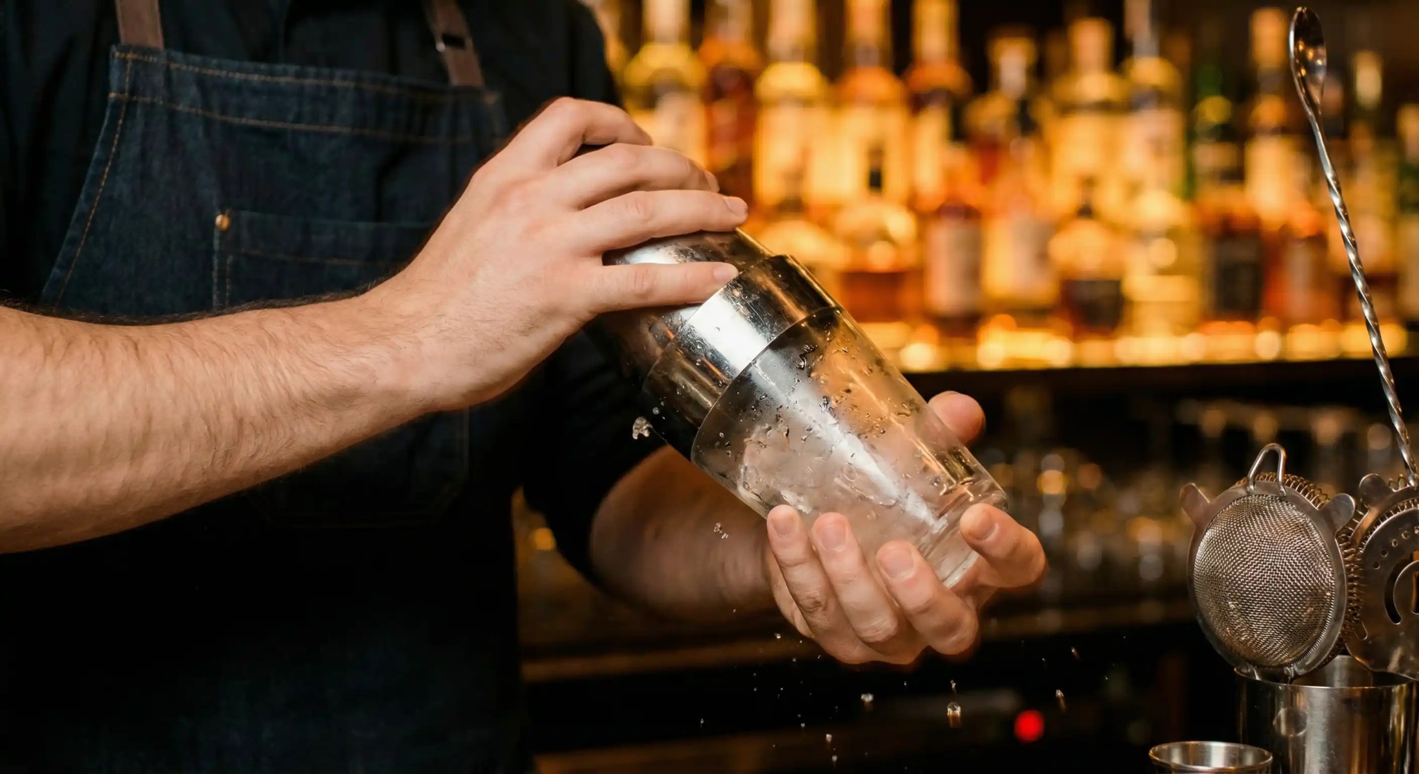 Bar back shelf and spirits display for bartending classes with organized liquor bottles and glassware